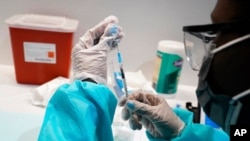 Seorang petugas kesehatan mengisi jarum suntik dengan vaksin Pfizer COVID-19, di Museum Sejarah Alam Amerika di New York, 22 Juli 2021. (Foto: AP)