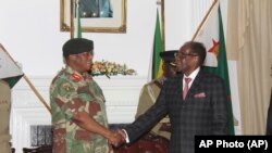 Presiden Zimbabwe Robert Mugabe (kanan) berjabat tangan dengan Jenderal Angkatan Darat Constantino Chiwenga sebelum menyampaikan pidato yang disiarkan secara langsung dari Harare, 19 November 2017. 
