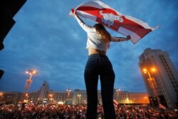 20일 벨라루스 민스크 독립광장에서 열린 반정부 집회에서 한 참가자가 이전 국기를 들고 있다.