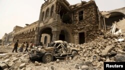 Houthi militants stand in front of the Defense Ministry compound after it was hit by Saudi-led airstrikes in Yemen's capital Sana'a, June 10, 2015. 