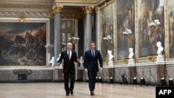 ប្រធានាធិបតី​រុស្ស៊ី Vladimir Putin (ឆ្វេង) កំពុង​ធ្វើ​ដំណើរ​ជាមួយ​ប្រធានាធិបតី​បារាំង Emmanuel Macron ដើម្បី​ចូលរួម​ក្នុង​សន្និសីទ​សារព័ត៌មាន​នៅ​រាជវាំង Versailles នៅ​ជិត​ទីក្រុង​ប៉ារីស។