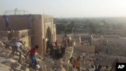 FILE - In this July 24, 2014 file photo, people walk on the rubble of the destroyed Mosque of The Prophet Younis, or Jonah, in Mosul, 225 miles (360 kilometers) northwest of Baghdad, Iraq. 