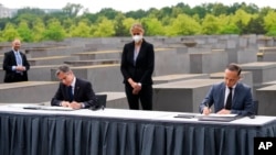 Američki državni sekretar Antony Blinken (L) i njemački ministar inostranih poslova Hajko Mas potpisuju sporazum o pokretanju Dijaloga SAD i Nejmačke o holokaustu, pored spomenika žrtvama holokausta u Berlinu (Foto: AP/Markus Schreiber)