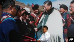  在中国西南部四川省成都市的一家酒店里，一名男子拿着雨伞走过一张中国国家主席习近平会见少数民族的照片。（2020年9月9日）