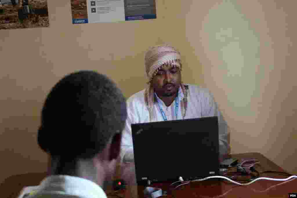 UNHCR's repatriation representative, Maawiya Issa, talks a refugee through the voluntary repatriation process, Dadaab, Kenya, April 24, 2015. (Mohammed Yusuf/VOA)