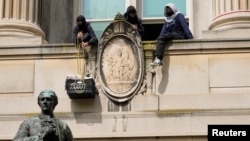 在哥伦比亚大学，一名学生抗议者从汉密尔顿楼的一座阳台把装着食物的框子吊上来。(2024年4月30日)