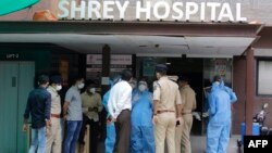 Petugas forensik, mengenakan alat pelindung diri, berbicara dengan polisi dan pejabat pemerintah di rumah sakit Shrey, di Ahmedabad, India, pasca kebakaran, Kamis, 6 Agustus 2020.

