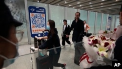 FILE- Passengers walk out of the International arrival hall of the Beijing Capital International Airport in Beijing, March 14, 2023.