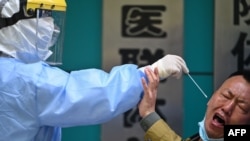 A man being tested for COVID-19 reacts as a medical worker takes a swab sample in Wuhan in China's central Hubei province on April 16, 2020. 