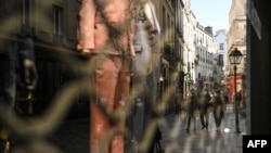 People walk near closed shops in Paris on March 20, 2021, on the first day of a new lockdown in France aimed to curb the spread of the COVID-19 cases.