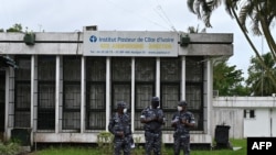 FILE - Police officers wearing face masks stands outside the Pasteur Institute of Ivory Coast, near Abidjan, May 11, 2020.