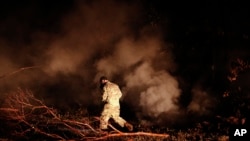 Sgt. 1st Class Carl Satterwaite, of the U.S. National Guard, tests air quality near cracks emitting volcanic gases from a lava flow in the Leilani Estates subdivision near Pahoa, Hawaii Thursday, May 10, 2018. Kilauea has destroyed more than 35 structures