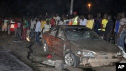 Warga berkumpul di dekat sebuah mobil yang hancur karena ledakan bom di Abuja, Nigeria (1/5).