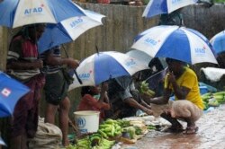 Rohingya refugees hide under umprellas during rainfall at Kutupalong refugee camp in Ukhia, Cox's Bazar, Bangladesh, Sept. 12, 2019.