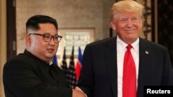 Presiden AS Donald Trump (kanan) dan pemimpin Korea Utara Kim Jong Un dalam pertemuan pertama di Singapura, 12 Juni 2018. 