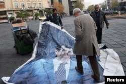 Pria berjalan melewati poster Assad yang dibersihkan setelah pemberontak mengumumkan penggulingannya di Damaskus, 10 Desember 2024. (Foto: Reuters)