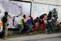 Members of the press take cover as clashes with police break out at the end of an anti-government march called by the artist community in Port-au-Prince, Haiti, Oct. 20, 2019.