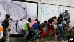 FILE - Members of the press take cover as clashes with police break out at the end of an anti-government march called by the artist community in Port-au-Prince, Haiti, Oct. 20, 2019.