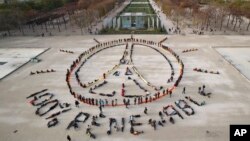 Environmentalist activists form a human chain representing the peace sign and the spelling out "100% renewable", on the side line of the COP21, United Nations Climate Change Conference near the Eiffel Tower in Paris, Sunday, Dec. 6, 2015. 