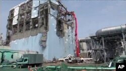 A concrete pumping vehicle sprays water to the spent fuel pool of No.4 reactor at Tokyo Electric Power Company's Fukushima Daiichi Nuclear Power Station in Fukushima prefecture in this handout photo taken May 6, 2011 and released by TEPCO on May 17, 2011