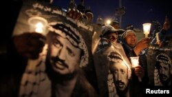 Palestinians hold candles and posters depicting late Palestinian leader Yasser Arafat during a rally marking the 9th anniversary of his death in Jerusalem's Old City on November 11, 2013.