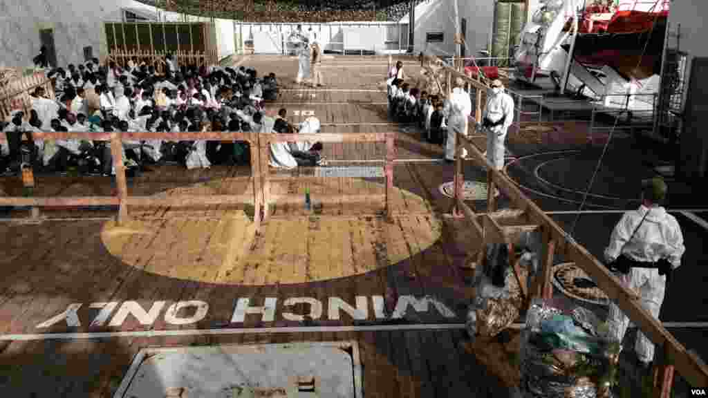 Des militaires norvégiens encadrent des migrants qui débarquent du bateau à Messine, Sicile, 6 octobre 2015 (Nicolas Pinault/VOA).