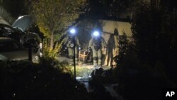 FILE - Two members of a police bomb squad carry a device to a sand-bagged area to be detonated as terror raids are carried out at Greenvale, near Melbourne, Australia, May 8, 2015.