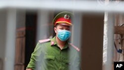 FILE - A police officer guards the barricaded entrance of an alley where one of its residents is has COVID-19 in Hanoi, Vietnam, July 29, 2020.