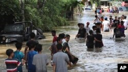 People wade through a flooded neighborhood in Tanggerang outside Jakarta, Indonesia, Thursday, Jan. 2, 2020. (AP Photo/Tatan Syuflana)