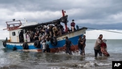 Local fisherman help ethnic Rohingya people as they arrive on Lancok Beach, North Aceh, Indonesia, June 25, 2020