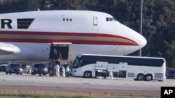 Personnel in protective clothing unload luggage from the airplane carrying U.S. citizens being evacuated from Wuhan, China, at March Air Reserve Base in Riverside, Calif. Jan. 29, 2020. 