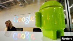 FILE - Google Android figurine sits on the welcome desk as employee Tracy McNeilly smiles at the new Google office in Toronto. 