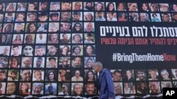 하마스에 붙잡힌 인질 240명 석방을 요구하는 예루살렘 시내 게시물 앞으로 24일 주민이 지나가고 있다.