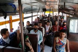 Migrant laborers and their families, who arrived from Gujarat state on a train, sit inside a bus as they prepare to leave for their native villages in their home state of Uttar Pradesh in Prayagraj, India, May 6, 2020.