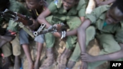 FILE - Young boys sit with their rifles Pibor, South Sudan, Feb. 10, 2015. U.N. officials say an estimated 30,000 people in the area have been displaced after days of deadly violence involving two ethnic groups, in December 2022.