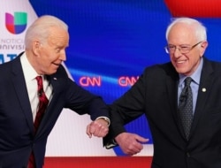 FILE - Former U.S. vice president Joe Biden, left, and Senator Bernie Sanders greet each other with an elbow bump before the start of the 11th Democratic Party 2020 presidential debate in a CNN Washington Bureau studio in Washington, March 15, 2020.