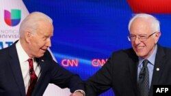 FILE - Joe Biden and Senator Bernie Sanders greet each other with a safe elbow bump before the start of the 11th Democratic Party 2020 presidential debate in a CNN Washington Bureau studio in Washington, March 15, 2020.