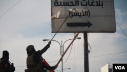 Iraqi soldiers tear down a sign pointing towards an Islamic State security office where locals were punished with whippings and other beatings, taken on Jan. 19, 2017 in Mosul, Iraq. (H.Murdock/VOA)