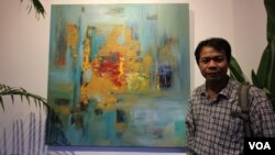 Chhim Sothy, a Cambodian artist, pose in front of his painting at the launching of his exhibition called "Consuming Passion" at the Plantation Hotel in Phnom Penh, Cambodia, on June 25, 2015. 