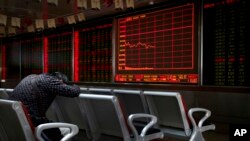 Seorang investor tertidur depan layar elektronik yang menampilkan informasi harga saham di sebuah perusahaan pialang di Beijing, China, 17 September 2018.