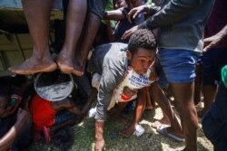 A resident crawls away with a donated bag of rice after residents overtook a truck loaded with earthquake relief supplies, in Vye Terre, Haiti, Aug. 20, 2021.