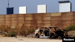 FILE - Prototypes for U.S. President Donald Trump's border wall with Mexico are seen behind the current border fence in this picture taken from the Mexican side of the border in Tijuana, Oct. 12, 2017. 