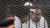 Political activists Ahmed Maher, Ahmed Douma (L) and Mohamed Adel (R) of the 6 April movement look on from behind bars in Abdeen court in Cairo, December 22, 2013. Three leading Egyptian activists were sentenced to three years in prison each. 