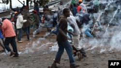 Residents run from teargas after throwing stones towards Kenyan police officials as they clash at Katwekera village within Kibera slum - a stronghold of opposition leader Raila Odinga - in Nairobi on October 26, 2017. (AFP PHOTO / TONY KARUMBA)