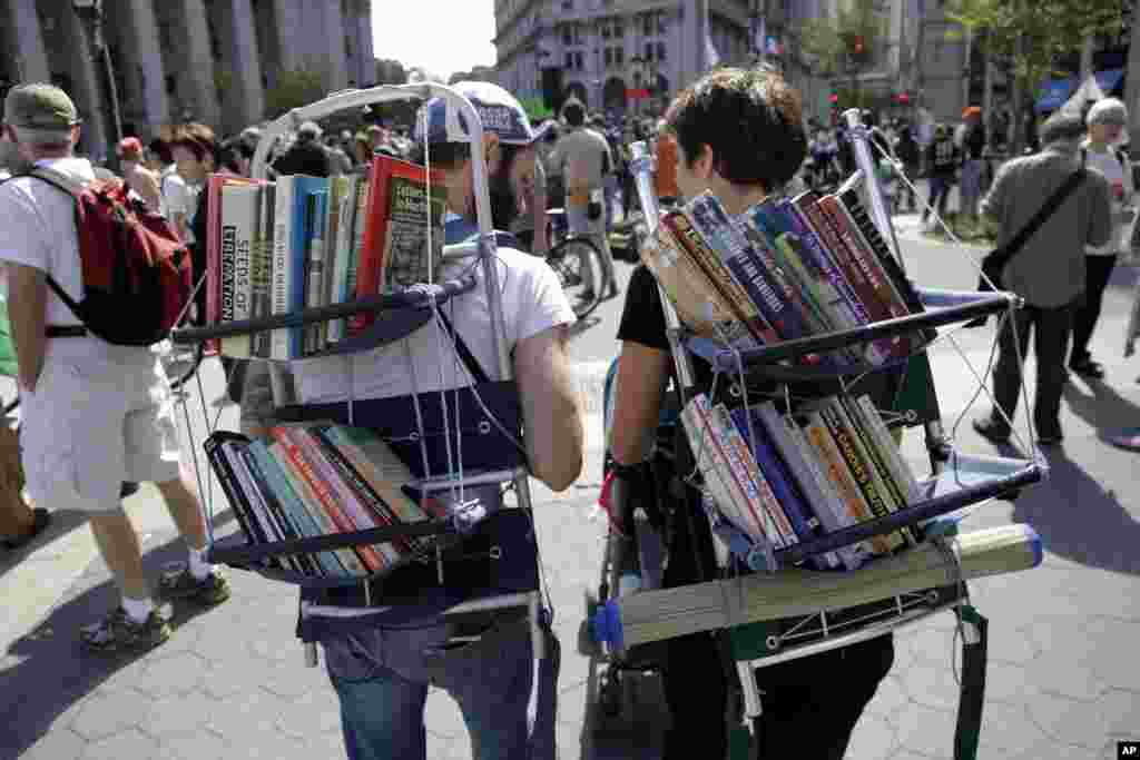 Nathaniel Katz, left, and Valentina Curandi carry a small pacifist library on their backs during an Occupy Wall Street anniversary concert in Foley Square in New York, September 16, 2012.
