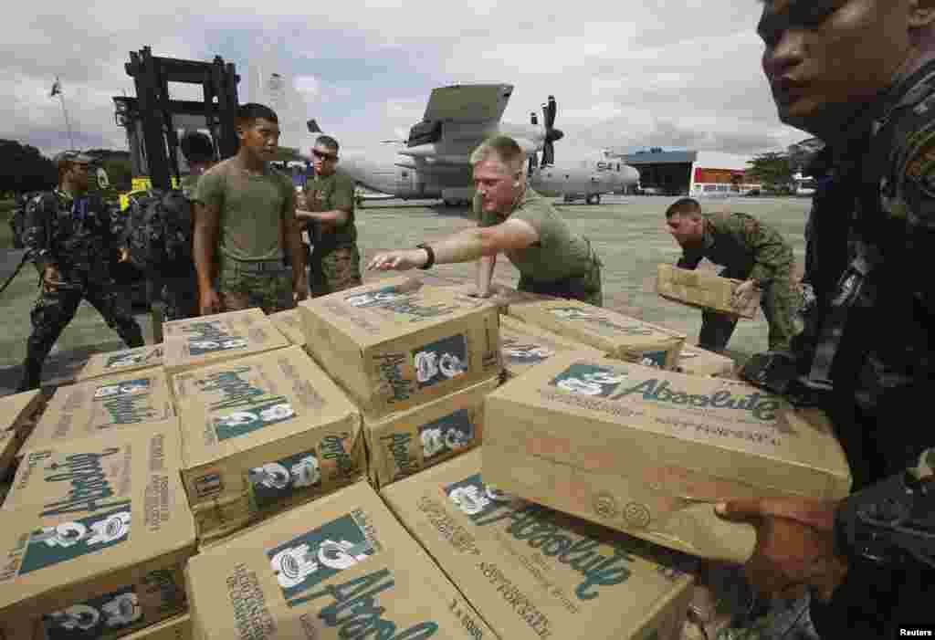 Personel militer Filipina dan AS bersiap mengangkut barang bantuan ke atas pesawat militer AS C130 untuk para korban Topan Haiyan, di markas angkatan udara Villamor di Manila. (Reuters/Cheryl Ravelo)