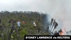 Des gens en train d'étaindre le feu se propage entre le camp Horombo et Mandara sur le mont Kilimandjaro, en Tanzanie, le 12 octobre 2020. Photo obtenue à partir des médias sociaux. (Sydney Lawrence / Collège de gestion de la faune africaine, Mweka / via Reuters)