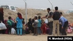Families wait by the fence as soldiers screen incoming refugees in Khazir Camp in the Kurdish region of northern Iraq, Oct. 28, 2016. 