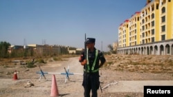 FILE - A Chinese police officer takes his position by the road near what is officially called a vocational education center in Yining in Xinjiang Uighur Autonomous Region, China, Sept. 4, 2018. 