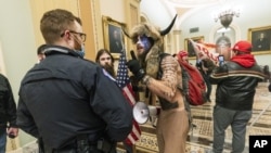 FILE - In this Jan. 6, 2021, file photo supporters of President Donald Trump are confronted by U.S. Capitol Police officers outside the Senate Chamber inside the Capitol in Washington. An Arizona man seen in photos and video of the mob wearing a fur hat w